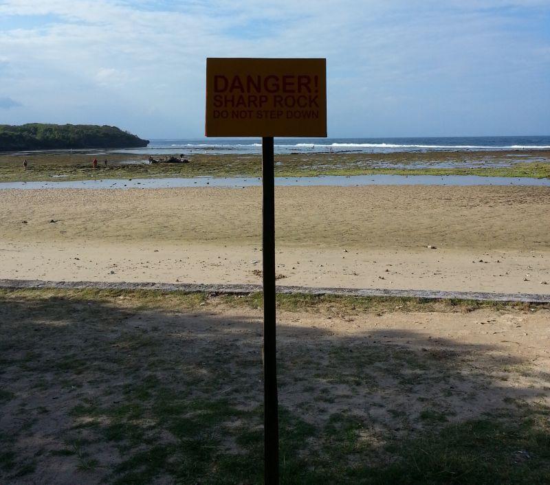 Пляж во время отлива. Табличка предупреждает об остром дне